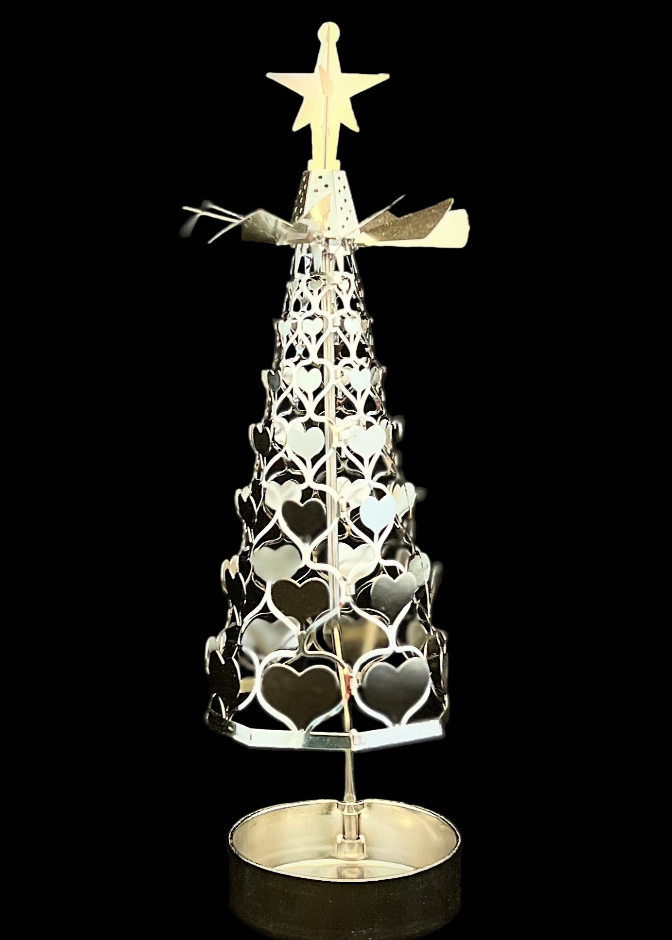 Decorative metal Christmas tree with star on top against a black background