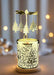 Decorative candle holder with Christmas tree design and hanging earrings on a black background