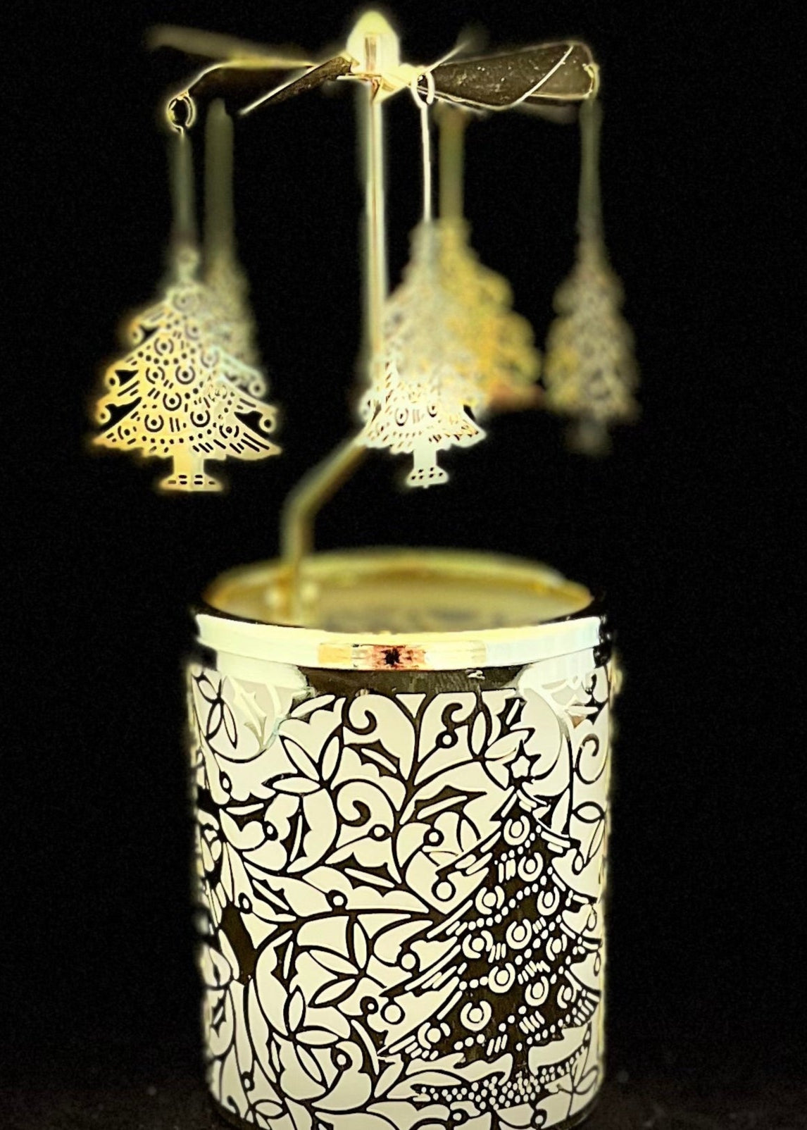 Decorative candle holder with tree-shaped wick trimmers on a black background
