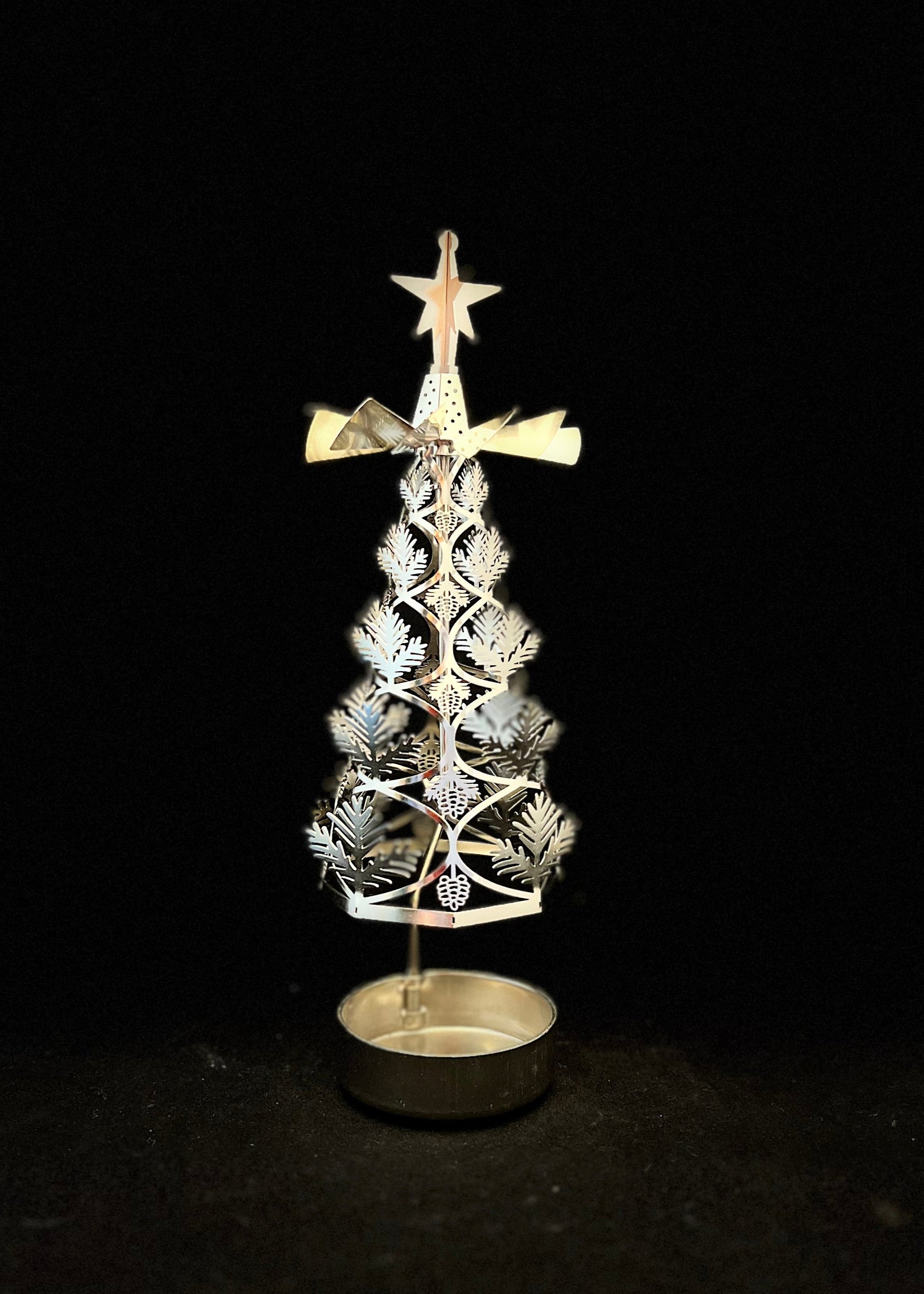 Decorative metal Christmas tree with star on top against a black background