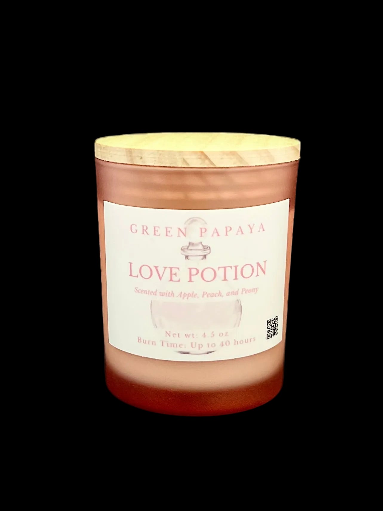 A jar candle labeled 'Green Papaya Love Potion' with a light wood lid, set against a solid black background.