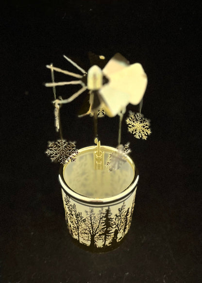 A small decorative wind spinner set in a cup with a forest pattern, photographed against a solid black background.
