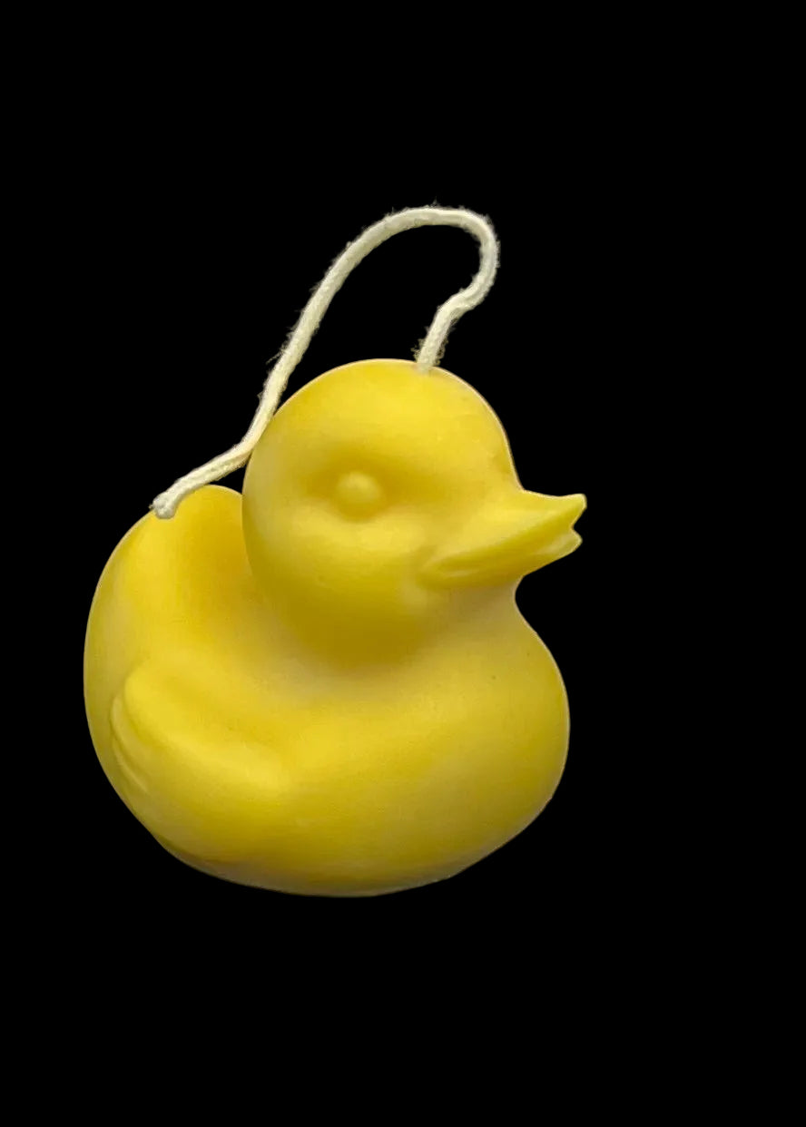 A yellow duck-shaped candle with a white hanging string, photographed against a solid black background.