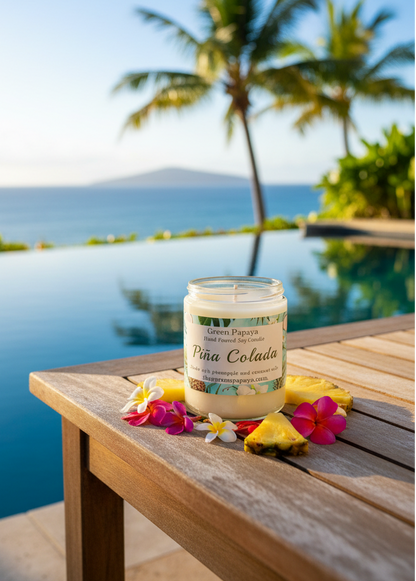 Jar of 'Pina Colada' candle on a wooden table by a pool with palm trees in the background