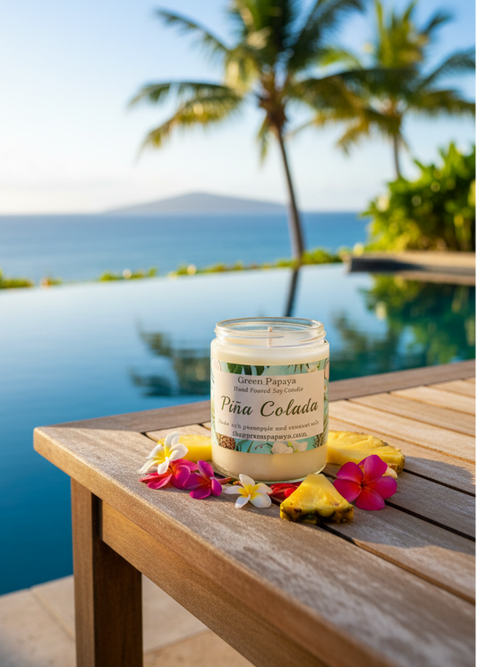 Jar of 'Pina Colada' candle on a wooden table by a pool with palm trees in the background